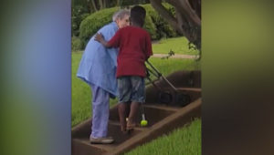 Black kid helps older White Woman up the stairs.