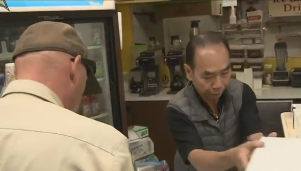 Customers of all races help Asian Donut shop owner.